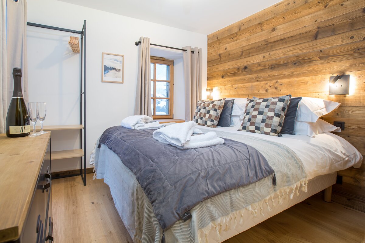 A bottle of champagne sits on a dresser next to a bed