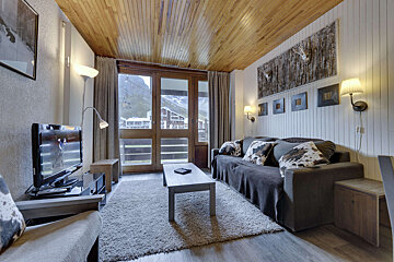 A living room with a table and chairs and a flat screen tv