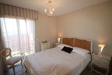A bedroom with a large bed and a chandelier