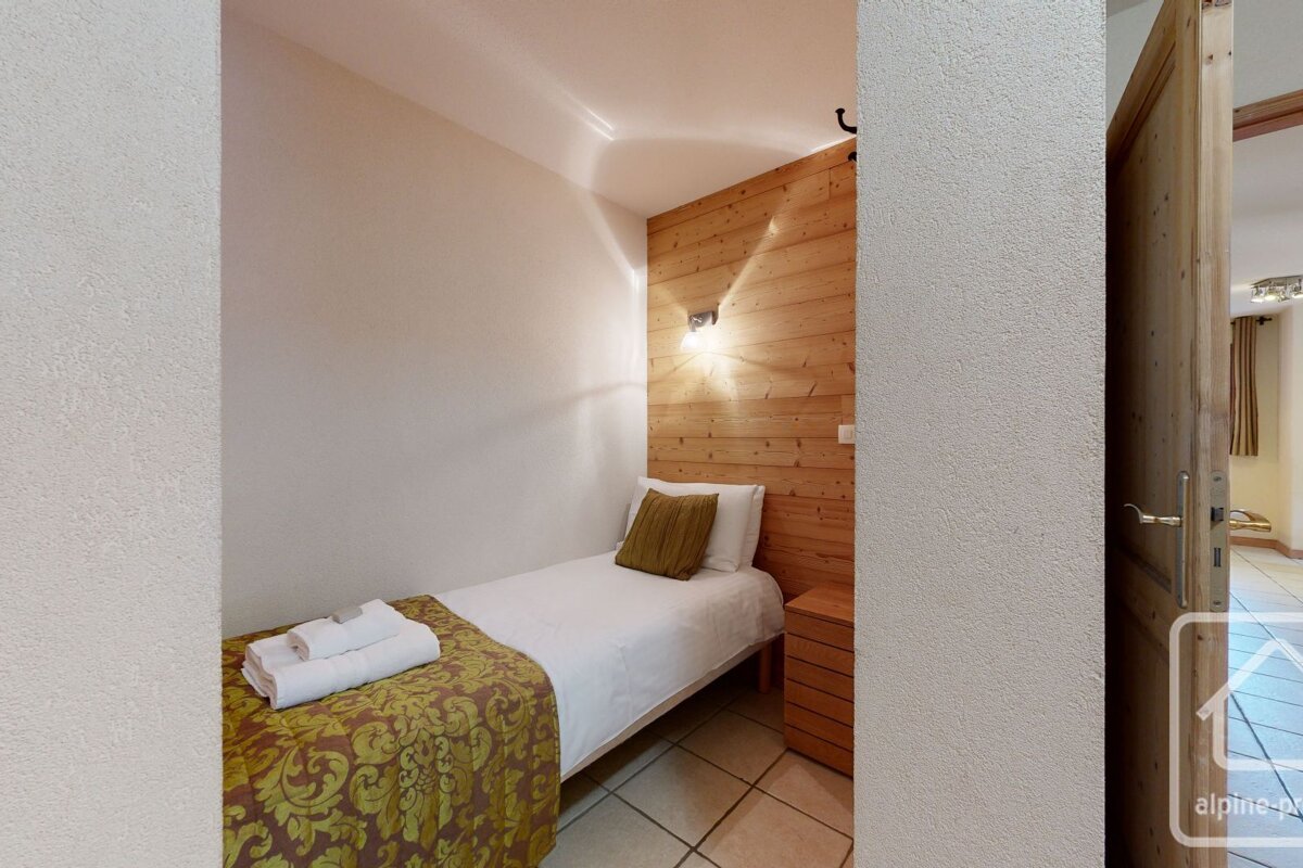 A bedroom with a single bed and a wooden wall