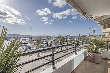 A balcony overlooking a marina with boats and palm trees