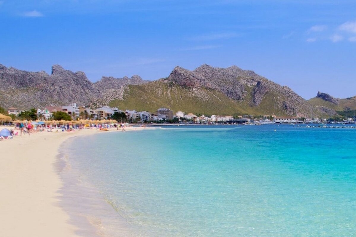 A beach with mountains in the background and umbrellas on the sand