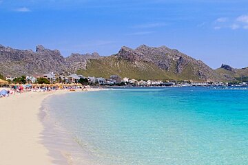 A beach with mountains in the background and umbrellas on the sand