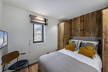 A bedroom with a bed a chair and a television