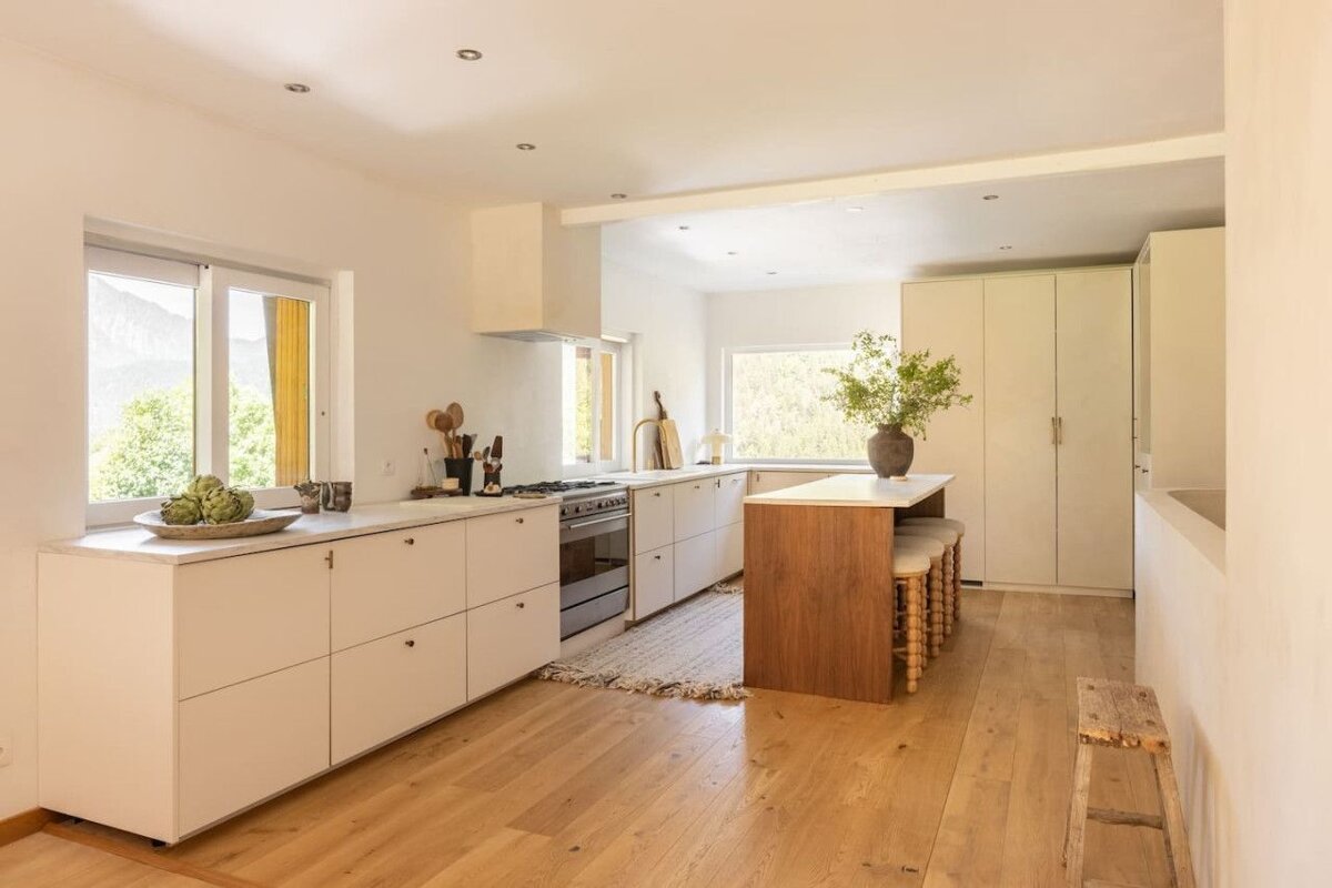 A kitchen with white cabinets and a wooden island