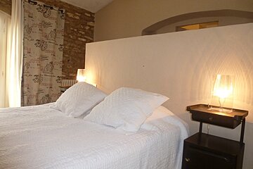 A bed with white sheets and pillows in a bedroom