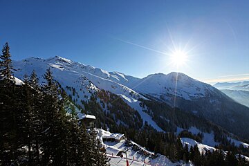 The sun is shining brightly on the snow covered mountains