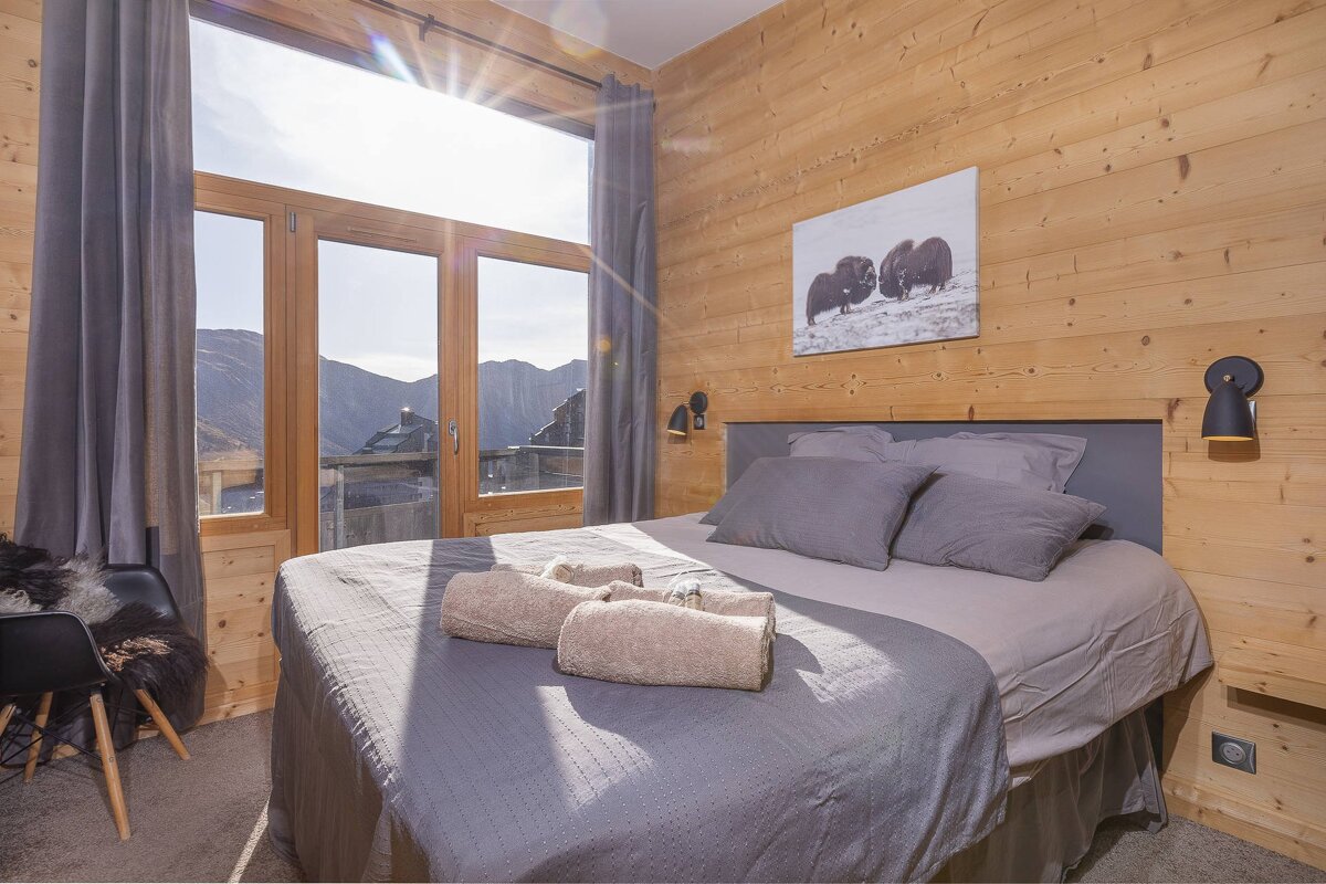 A bedroom with a painting of bison on the wall above the bed