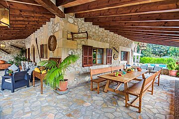 A wooden table with fruit on it sits under a wooden roof