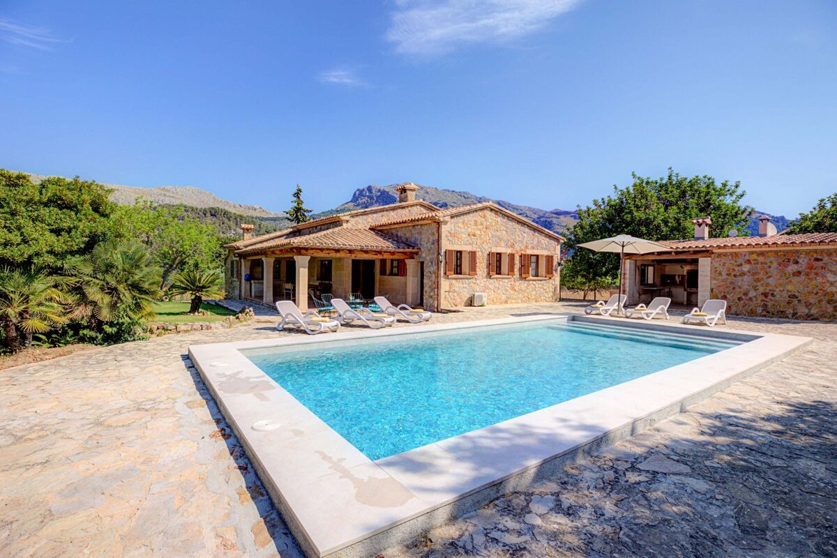 A large swimming pool in front of a stone house