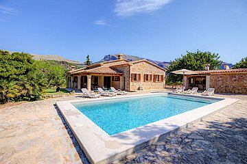 A large swimming pool in front of a stone house