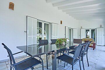 A table and chairs on a patio with white shutters