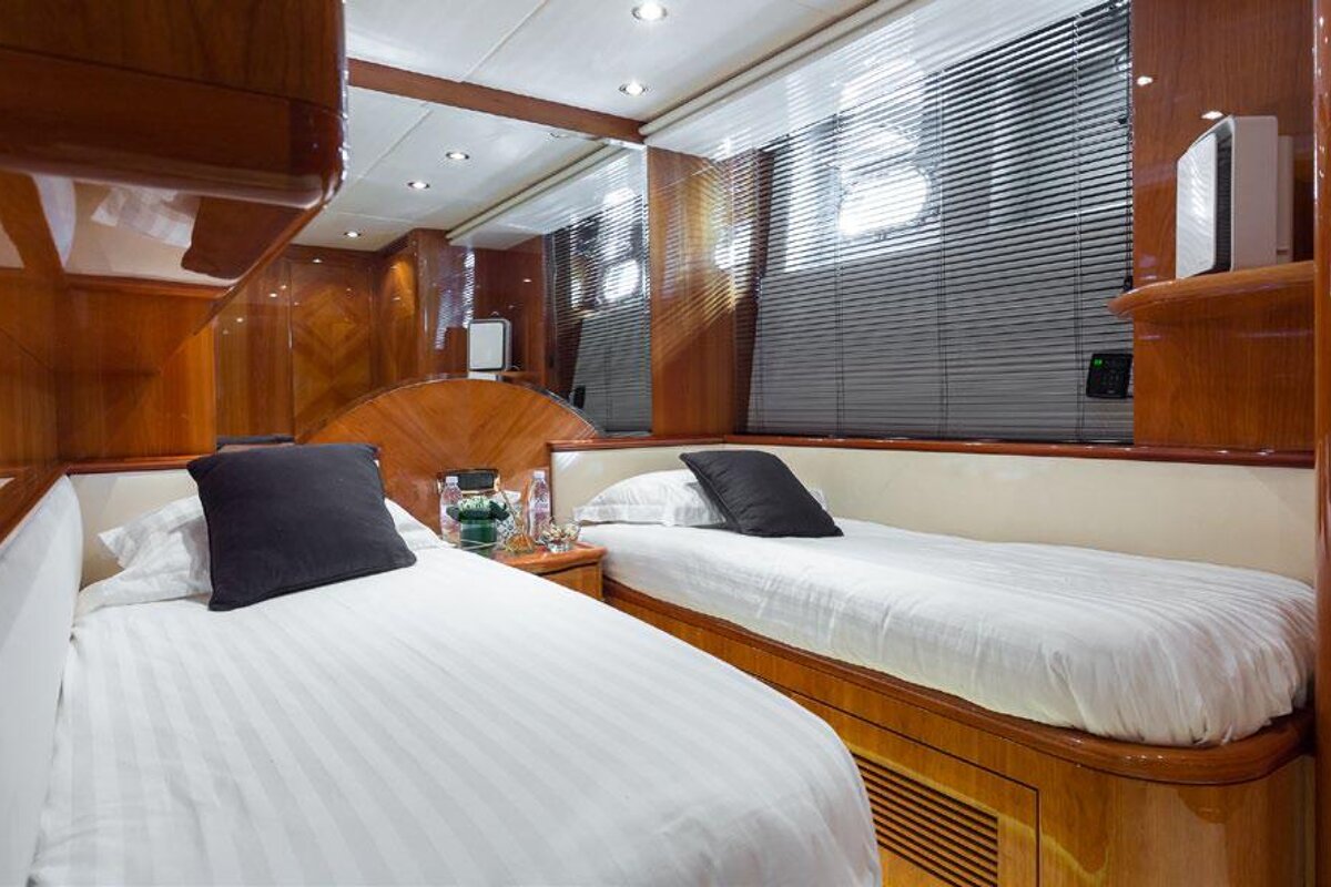 A bedroom with two beds and a window with blinds