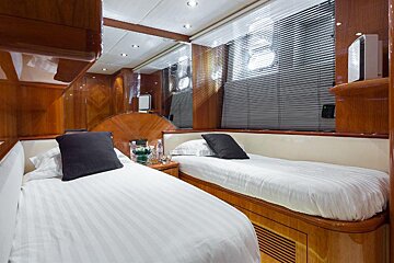 A bedroom with two beds and a window with blinds