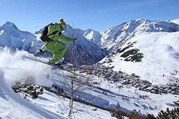 A person is skiing down a snow covered slope in the mountains