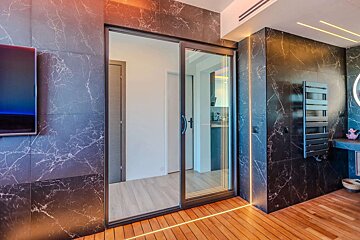 A bathroom with marble walls and a sliding glass door