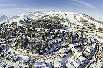 An aerial view of a snowy town with mountains in the background