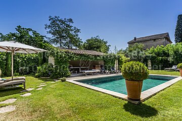 A large swimming pool is surrounded by lawn chairs and umbrellas