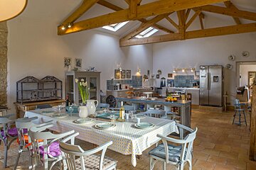 A dining room with a table and chairs and a stainless steel refrigerator