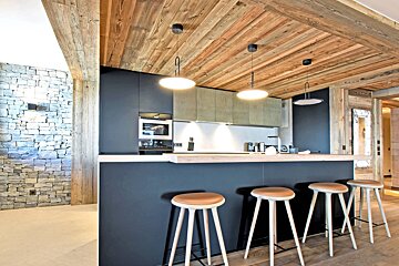 A kitchen with a wooden ceiling and black cabinets