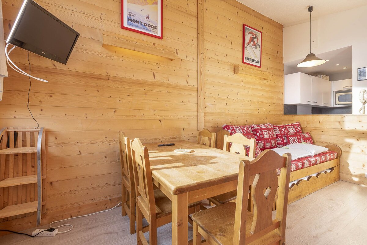 A living room with a table and chairs and a poster on the wall that says mont dore
