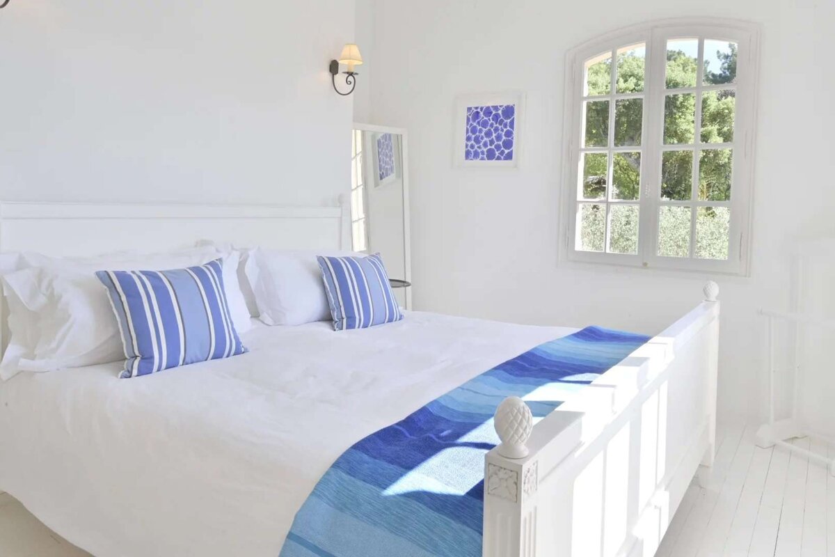 A bed with blue and white pillows and a blue blanket