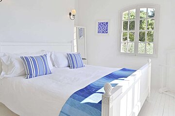 A bed with blue and white pillows and a blue blanket