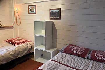 A bedroom with two beds and a white shelf