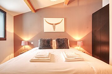 A bedroom with a painting of a bull on the wall above the bed