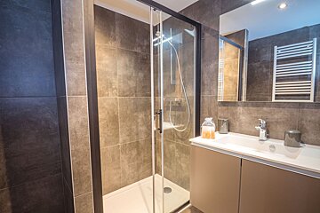 A bathroom with a walk in shower and a sink