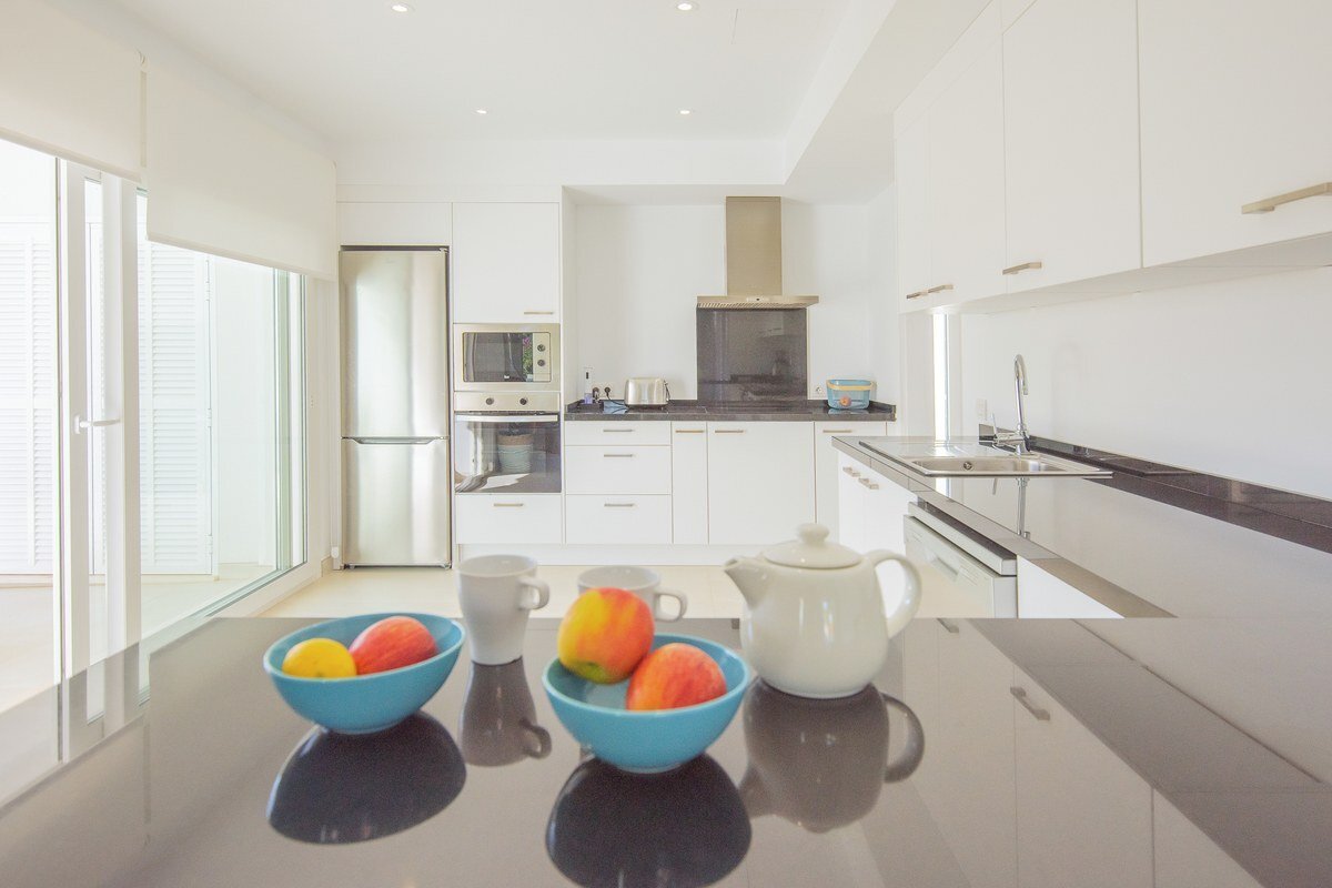 A kitchen with white cabinets and black counter tops