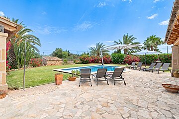A patio with chairs and umbrellas in front of a swimming pool