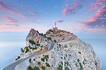 A road leads to a lighthouse on top of a mountain overlooking the ocean