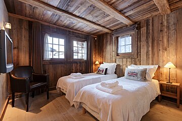 A bedroom with two twin beds and a chair