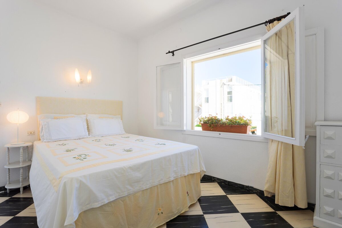 A bedroom with a bed and a window with a potted plant in it