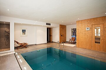A swimming pool is surrounded by a wooden sauna
