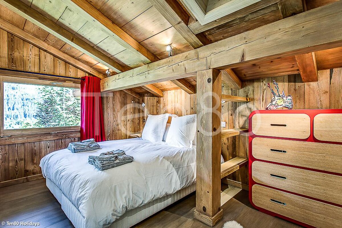 A bedroom with a large bed and a red dresser