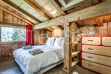 A bedroom with a large bed and a red dresser