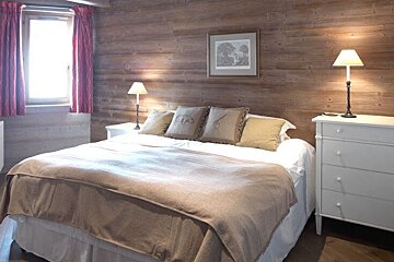 A bedroom with a bed dresser and two lamps