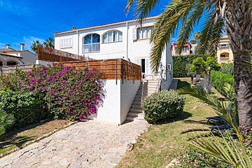 A white house with purple flowers in front of it