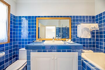A bathroom with blue tiles and white cabinets