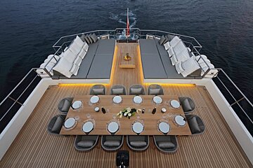A large wooden table and chairs on the deck of a boat