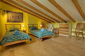 A bedroom with two beds and a rug on the wall