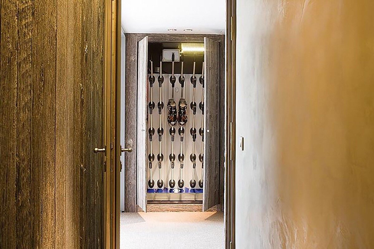 A hallway with a closet full of skis and boots