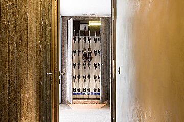 A hallway with a closet full of skis and boots