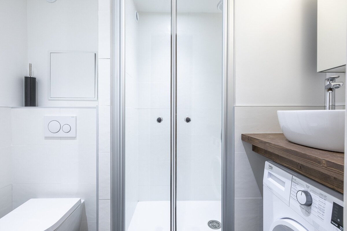 A bathroom with a washing machine and a toilet