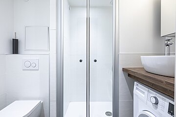 A bathroom with a washing machine and a toilet