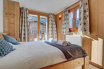 A bedroom with a bed and a window with floral curtains