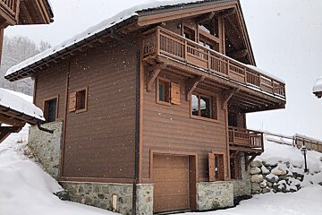A snowy house with a garage and a balcony