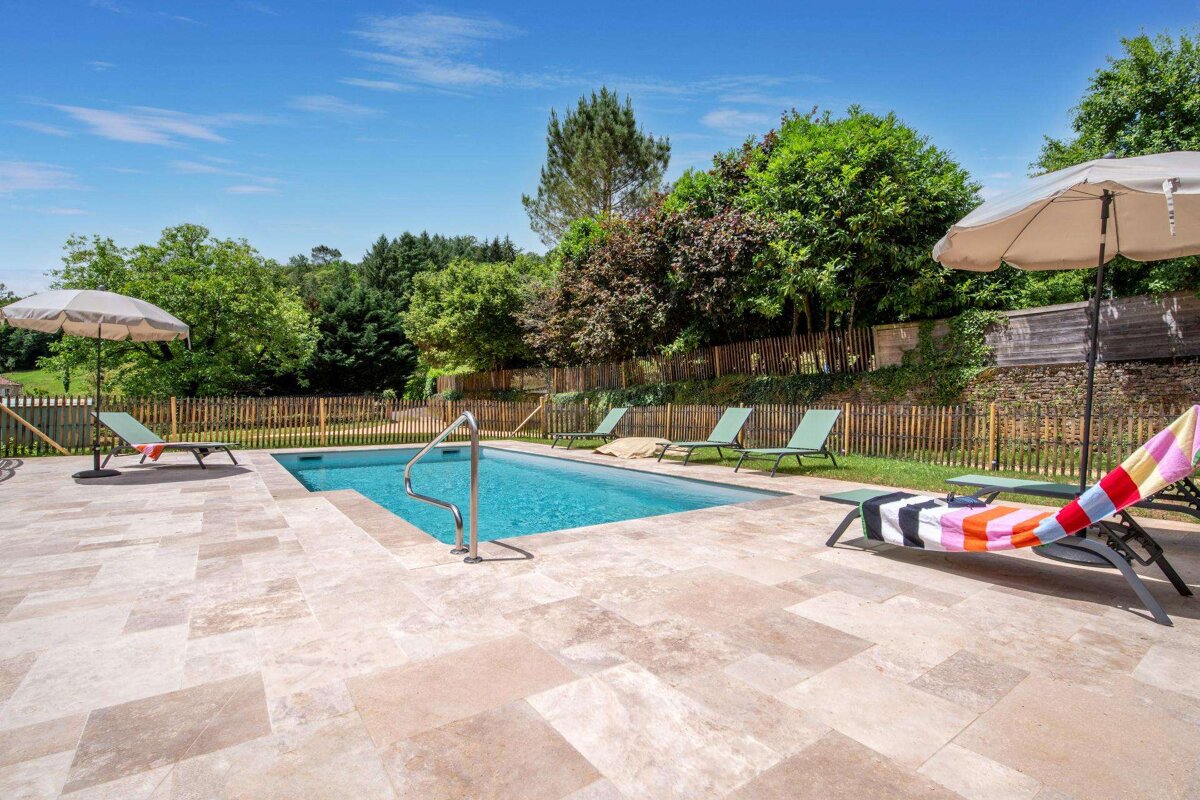 A swimming pool with chairs and umbrellas around it